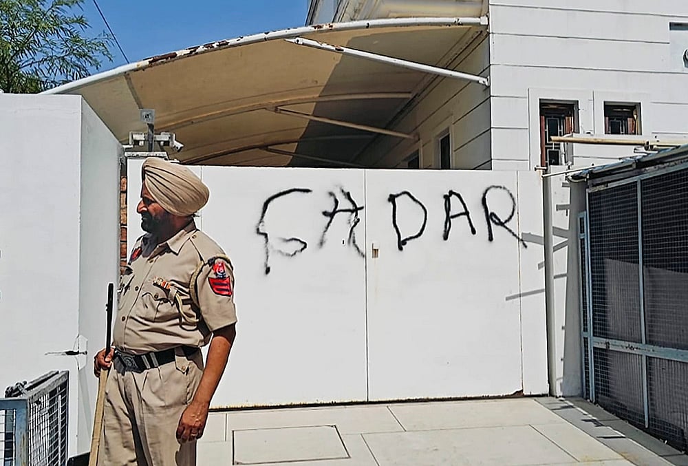 | Photo: PTI : A police official stands guard after AAP workers allegedly wrote Gaddar, a traitor, with spray paint on the entrance gate of Rajya Sabha MP Harbhajan Singh, a day after he quit the former party and joined the BJP, in Jalandhar, Punjab.