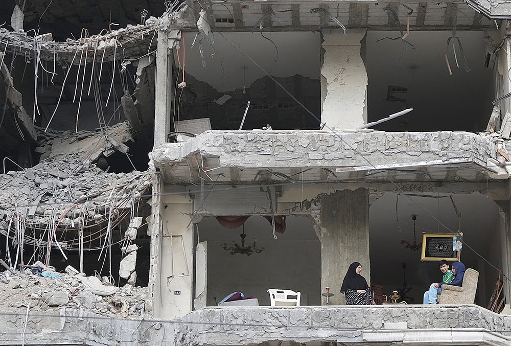 | Photo: AP/Hassan Ammar : The wife and children of Fadi Al Zein, who lost both his homes in Israeli strikes in his village of Khiam and in Dahiyeh, sit on the balcony of their heavily damaged apartment building in Beiruts southern suburbs, Lebanon, Saturday, April 25, 2026. 