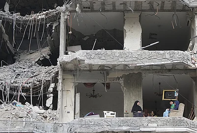 | Photo: AP/Hassan Ammar : The wife and children of Fadi Al Zein, who lost both his homes in Israeli strikes in his village of Khiam and in Dahiyeh, sit on the balcony of their heavily damaged apartment building in Beiruts southern suburbs, Lebanon, Saturday, April 25, 2026.