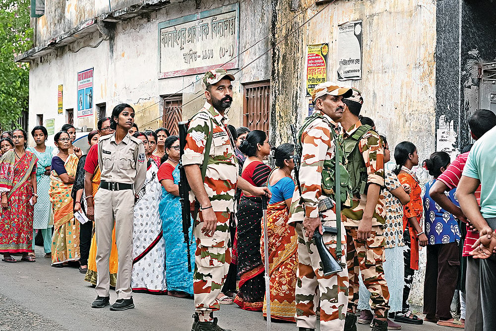 | Photo: Sandipan Chatterjee : Guns and Forces: Voters line up to cast their vote in the second phase of the West Bengal election amid heavy security