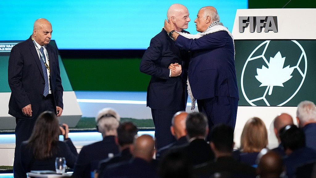 Darryl Dyck/The Canadian Press via AP : Palestinian Football Association president Jibril Rajoub, right, reaches to kiss FIFA president Gianni Infantino on the cheek after speaking as Israel Football Association vice-president Basim Sheikh Suliman, left, watches during the 76th FIFA Congress in Vancouver, British Columbia.