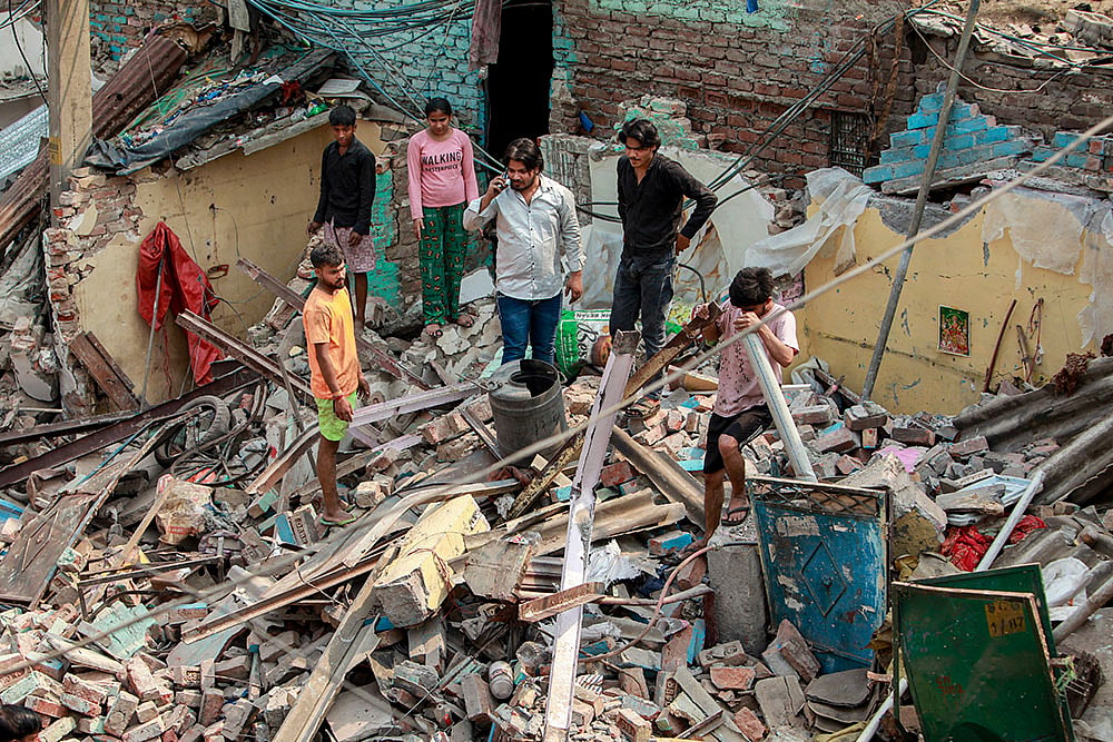 | PTI Photo : New Delhi: People gather at a demolished structure after an anti encroachment drive was carried out by Municipal Corporation of Delhi (MCD) at Wazirpur industrial area, in New Delhi.