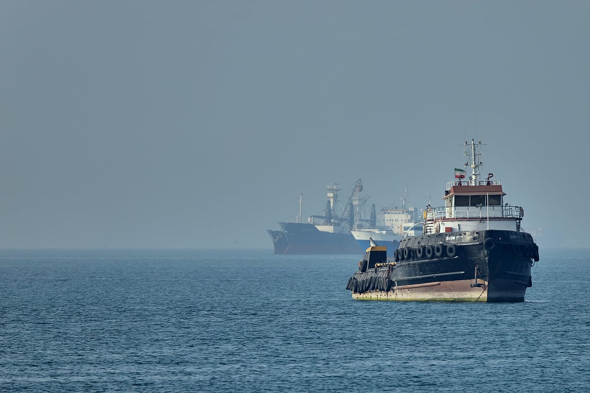 PTI : An Iranian tugboat floats in the foreground as cargo ships sit at anchor in the Strait of Hormuz off Bandar Abbas, Iran.
